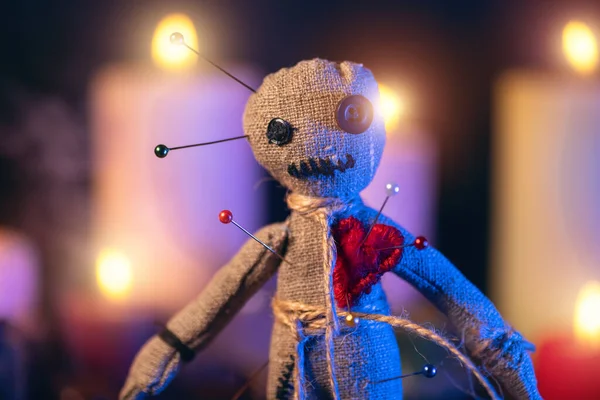 Boneka Voodoo diisi dengan jarum dengan hati kain merah ditindik terhadap latar belakang lilin terbakar. Mengerikan atau ritual esoteris yang menyeramkan — Stok Foto