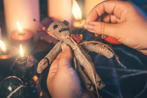 Les mains féminines collent des aiguilles dans le corps de la poupée vaudou en chiffon. La sorcière accomplit une sorcellerie sinistre. Concept de rituels occultes, ésotériques et mystiques — Photo