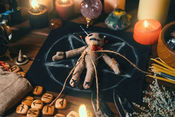 Lalka voodoo nabita igłami z przebitym czerwonym szmacianym sercem na pentagramie i wokół palących się świec. Straszny lub dziwaczny magiczny rytuał ezoteryczny — Zdjęcie stockowe