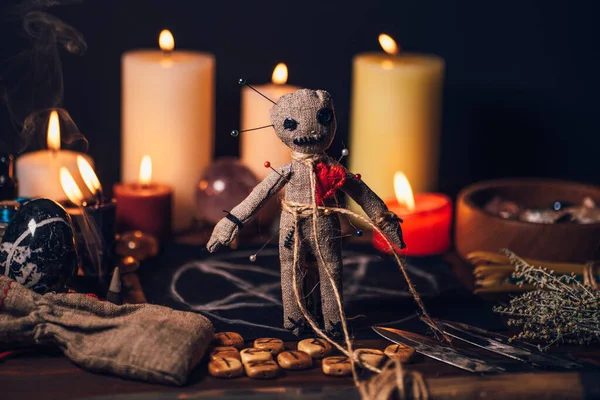 Boneka voodoo di atas meja ajaib dengan benda-benda esoterik dan membakar lilin untuk ritual balas dendam magis Stok Foto