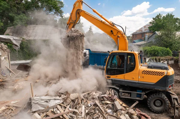 Penghancuran bangunan oleh ekskavator industri. Ember menghancurkan dinding dan atap rumah tua penuh debu — Stok Foto