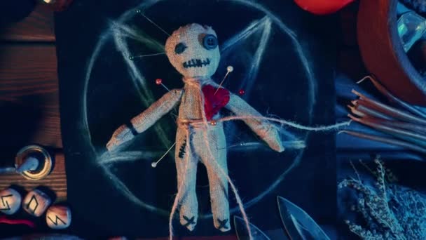 Karanlık ruhsal büyücülük masasında mumlar ve cadılar bayramı büyüsü ve laneti için sihirli özellikler taşıyan ürkütücü bir voodoo bebeği. — Stok video