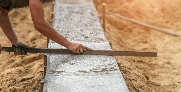 Trabajador nivelación de cemento recién vertido en encofrado con refuerzo, cimentación del edificio residencial —  Fotos de Stock