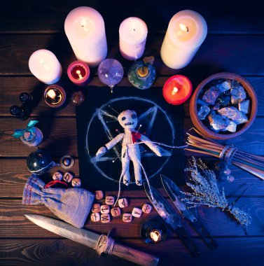 Creepy voodoo doll on dark scary spiritual wizardry table with candles and magic attributes for halloween sorcery and curse clipart