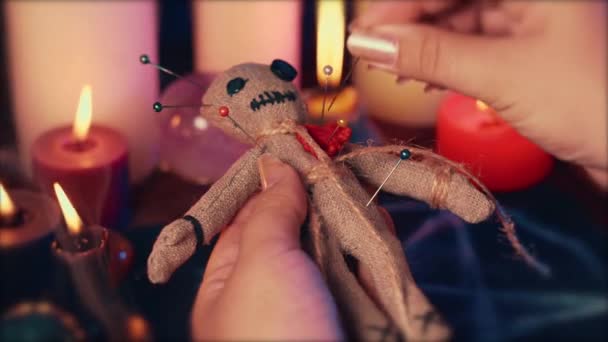 Boszorkány vagy boszorkány tűket szúrnak a voodoo babába a rituális asztalnál pentagrammal, égő gyertyákkal és más okkult tárgyakkal. Voodoo boszorkányság, spiritualitás és okkultizmus koncepció — Stock videók