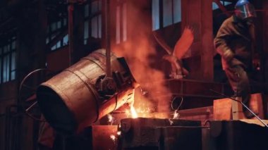 Metal döküm işlemi. Erimiş sıvı demir kepçe kabından küfe dökülüyor.