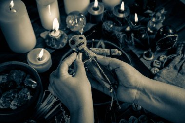 Büyücü ya da cadı pentagram, mum yakma ve diğer gizli nesnelerle ayin masasındaki vudu bebeğine iğne batırıyor. Vudu büyücülüğü, maneviyat ve okültizm kavramı