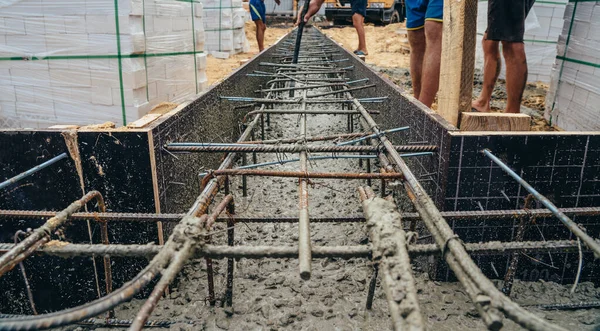 Заливка цемента или бетона автоматическим насосом, строительная площадка с усиленной решеткой фундамента, начало строительства нового дома — стоковое фото