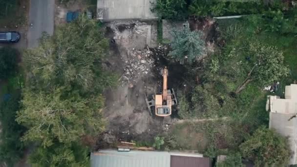 Aerial top view of yellow excavator at construction site after demolition of house — Stock Video