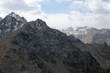 Zailiysky Alatau 'nun yüksek rakımlı vahşi doğasında, sivri dağ tepeleri ve karla kaplı tepelerin panoramik manzarası
