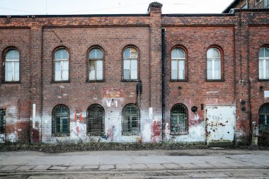 Gdansk 'taki İmparatorluk Tersanesi' ndeki (Stocznia Cesarska) 19. yüzyıldan kalma endüstriyel bir binanın ön görüntüsü. Kırmızı tuğla duvarda kemerli pencereler, metal ızgaralar ve tarihi el boyaması 