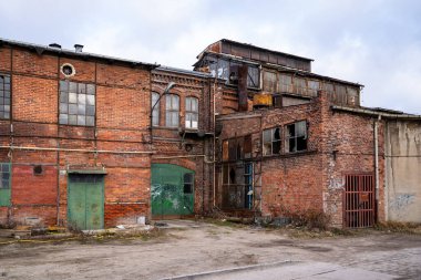 Polonya 'nın Gdansk kentindeki tarihi İmparatorluk Tersanesi' ndeki (Stocznia Cesarska) eski bir kırmızı tuğlalı sanayi binasının dış görünüşü. Silah sesi, kırılan camlar, graffitiler ve yıpranmış metal kapılar ile kentsel bozulmayı yakalıyor.