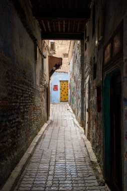 Fas 'ın dört imparatorluk şehrinden biri olan tarihi Meknes Medine' deki dar ve labirent geçidine çarpıcı bir manzara. Görüntü geleneksel Maghreb mimarisinin özünü yakalıyor, koyu mavi ve beyaz tonlarda desenli duvarları var.