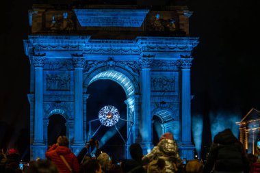 MILAN, İtalya - 18 Şubat 2026: Arco della Pace (Barış Kemeri) altında kurulan Milan Cortina 2026 Olimpiyat kazanı altında fotoğraf çeken turist ve vatandaşlardan oluşan bir kalabalık. Parlayan küresel kurulum, Marco Balich tarafından tasarlandı ve Leo 'dan esinlendi