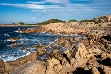 La Maddalena adasındaki Cala Francese 'in çarpıcı kıyı manzarası. Görüntü, rüzgarın şekillendirdiği ikonik pembe granit kaya oluşumlarını ve tarihi taş ocağının yanındaki takımadanın turkuaz sularını gösteriyor..