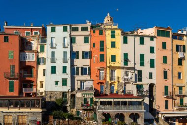 UNESCO Dünya Mirası sitesi Porto Venere 'in ikonik çok renkli cephelerinin canlı bir yakın çekimi. Görüntü, geleneksel Ligurian mimarisini ve tarihi sahil köyünün üzerinde yükselen San Lorenzo Kilisesi 'nin çan kulesini yakalıyor.