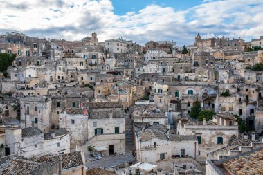 Matera 'nın antik troglodit yerleşiminin yer aldığı geniş açılı bir çekim. Evleri ve kiliseleri tüy taşına oyulmuş. Görüntü, Kanyon 'un kıyısına tünemiş Sasso Caveoso bölgesinin yoğun tarihi yapısını vurguluyor.