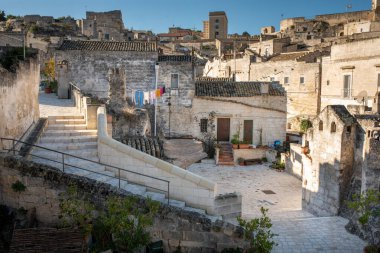 İtalya 'nın Sassi di Matera kentinin kalbindeki tipik bir ortak avlunun (vicinato) büyüleyici bir görüntüsü. Görüntü kendiliğinden tüy taşı mimarisi, karakteristik merdiven ve renkli çamaşırların doğal güneş ışığı altında kuruması üzerine kurulanmasını içeriyor.