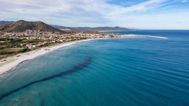 La Caletta kıyı şeridinin çarpıcı yüksek açılı manzarası, İtalya 'nın Sardinya kentindeki Siniscola köyü. Görüntü, arka planda kristal berraklığında turkuaz sularla çevrili uzun beyaz kumlu plajı, şehir merkezi ve marinayı da kapsıyor.
