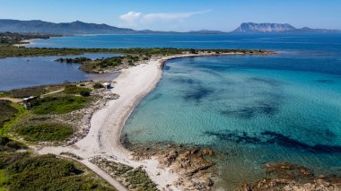 San Teodoro, Sardunya 'nın kuzeydoğusundaki Isuledda Sahili' nin çarpıcı bir kıyı manzarası. Görüntü, ince beyaz kumu, kristal berraklığında turkuaz suları ve tipik Akdeniz çalılarını yakalıyor. Arka planda, Tavolara I 'in görkemli silueti.