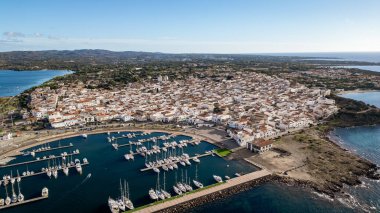 Kenetlenmiş yelkenli tekneleri ve tarihi kasabanın karakteristik beyaz evleriyle Calasetta limanının göz kamaştırıcı yüksek açılı manzarası. Sardunya 'nın güneybatısında yer alan bu kıyı köyü Tabarchine mirası ve kristal-clea ile ünlüdür.