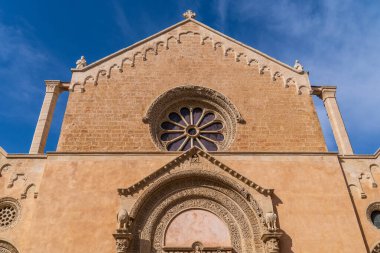 Puglia 'daki Santa Caterina Bazilikası' nın taş cephesinin ayrıntıları. Karmaşık bir şekilde oyulmuş 14. yüzyıl gül penceresi ve stilofor aslanları ve dekoratif kemerleri olan Gotik bir portal. Salento bölgesinde bir Romanesk-Gotik başyapıtı.