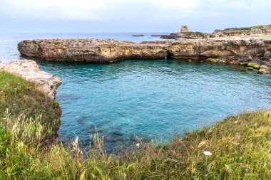 Melendugno 'daki Roca Vecchia' nın panoramik görüntüsü. Turkuaz şeffaf sular 16. yüzyıl Maradico Kulesi kalıntılarının hakim olduğu kireçtaşı kayalıklarına çarptı. Salento, Apulia, İtalya 'nın kalbindeki el değmemiş kıyı manzarası.