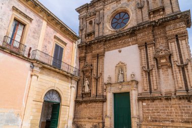 Nardo 'daki Lekesiz Gebelik Kilisesi' nin barok görünüşü. Carparo taşı, süslü kapılar, Nikes aziz heykeller ve Salento, Puglia, İtalya 'da sisli bir gökyüzünün altında şeftali rengi tarihi bir binanın yanında bir gül penceresi..