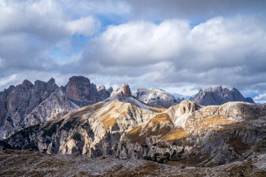 Tırtıklı Cadini di Misurina tepeleri ve Sexten Dolomites 'in geniş panoramik manzarası. Dramatik bulutlu bir gökyüzünün altında, yüksek irtifada kayalık, güneşli arazi yamaçları var. İkonik alp manzarası, Kuzey İtalya 'da bir UNESCO Dünya Mirası sahası.