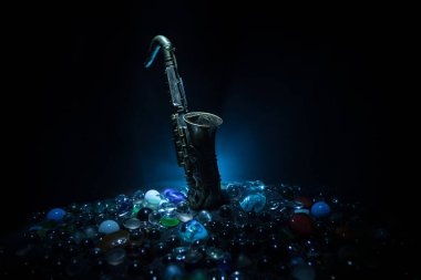 Müzik konsepti. Saksafon caz enstrümanı. Alto altın saksafon minyatürü, sisli arka planda renkli ışık. Düşük ışıkta saksafon müzik aleti. Seçici odak