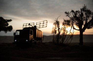 Yaratıcı sanat dekorasyonu. Gün batımında radar antenli mobil hava savunma aracı silueti. Akşam gökyüzüne karşı uydu anteni ya da radyo anteni. Seçici odak