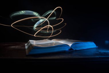 Bir yığın eski kitap. Ahşap masanın üzerinde antika bir kitap. Karanlıkta parlayan bir kitabın etrafında sihirli bir yıldırım. Seçici odak