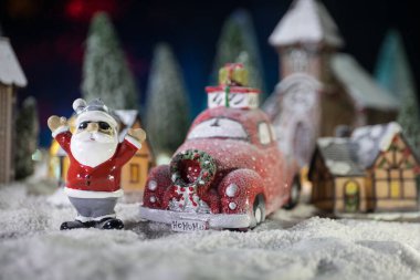 Noel ve yeni yıl tatili konsepti. Geceleri karlı küçük dekoratif evler. Geleneksel tatil özellikleri kar üzerindedir. Yaratıcı sanat dekorasyonları. Metnin için boş boşluk