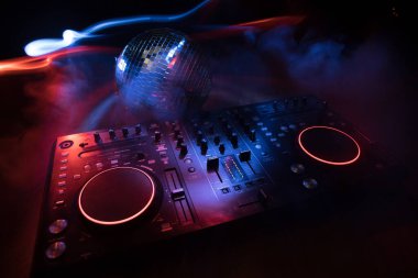 Kulüp müzik konsepti. DJ konsol masası renkli ışıkla karanlıkta DJ karıştırma masası. Karışık ekipman eğlence DJ istasyonu. Seçici odak