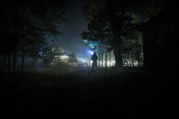 Silhouette of person standing in the dark forest with light. Horror halloween concept. strange silhouette in a dark spooky forest at night