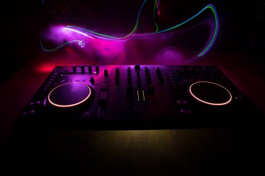 Kulüp müzik konsepti. DJ konsol masası renkli ışıkla karanlıkta DJ karıştırma masası. Karışık ekipman eğlence DJ istasyonu. Seçici odak