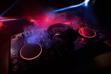 Kulüp müzik konsepti. DJ konsol masası renkli ışıkla karanlıkta DJ karıştırma masası. Karışık ekipman eğlence DJ istasyonu. Seçici odak