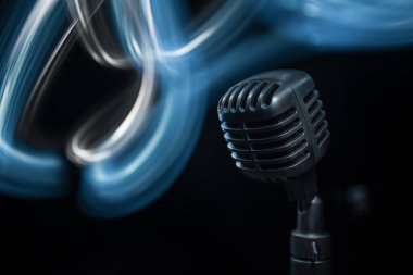 Arka planda arka ışıklandırmalı Retro tarzı mikrofon. Ses, müzik ve karaoke için klasik gümüş mikrofon. Konuşma yayın ekipmanı. Canlı pop, rock müzik performansı. Seçici odak