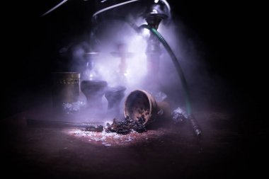 Shisha konsepti. Masada shisha hazırlıyorum. Ahşap masada kullanılmış shisha kasesi. Işıklı karanlık bir atmosfer. Seçici odak.