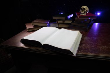 Bir yığın eski kitap. Ahşap masanın üzerinde antika bir kitap. Karanlıkta parlayan bir kitabın etrafında sihirli bir yıldırım. Seçici odak