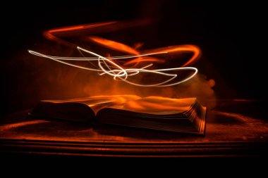 Bir yığın eski kitap. Ahşap masanın üzerinde antika bir kitap. Karanlıkta parlayan bir kitabın etrafında sihirli bir yıldırım. Seçici odak