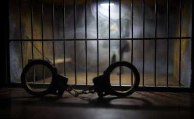 Hapisteki adam demir parmaklıklar arkasında. Eski edepsiz hapishane minyatürü. Karanlık hapishane iç dekorasyonu, kelepçeli. Seçici odak