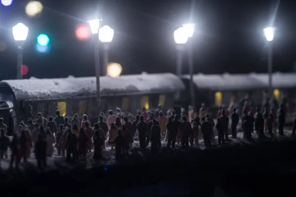 Silhouettes of a crowd standing at old vintage train on foggy background. Selective focus. Creative artwork decoration with toy train