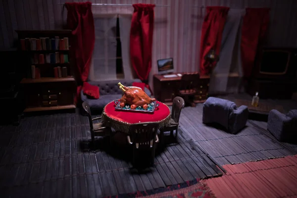 Thanksgiving holiday creative concept. A realistic dollhouse living room with furniture and window at night. Thanksgiving Turkey miniature on table. Selective focus