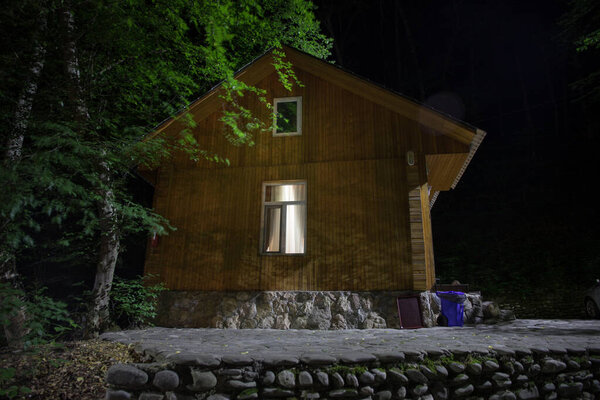 Old house with a Ghost in the forest at night or Abandoned Haunted Horror House in fog. Old mystic building in dead tree forest. Creepy house in the middle of a dark forest. Surreal lights