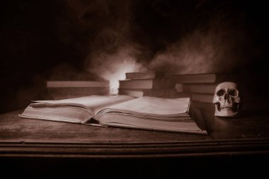 Bir yığın eski kitap. Ahşap masanın üzerinde antika bir kitap. Karanlıkta parlayan bir kitabın etrafında sihirli bir yıldırım. Seçici odak