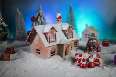 Noel ve yeni yıl tatili konsepti. Geceleri karlı küçük dekoratif evler. Geleneksel tatil özellikleri kar üzerindedir. Yaratıcı sanat dekorasyonları. Metnin için boş boşluk