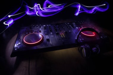 Kulüp müzik konsepti. DJ konsol masası renkli ışıkla karanlıkta DJ karıştırma masası. Karışık ekipman eğlence DJ istasyonu. Seçici odak