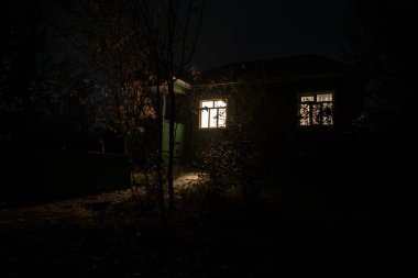 Geceleri ormanda bir hayaletin olduğu eski bir ev ya da terk edilmiş bir korku evi. Ölü ağaç ormanındaki eski mistik bina. Gerçeküstü ışıklar. Korku Cadılar Bayramı konsepti