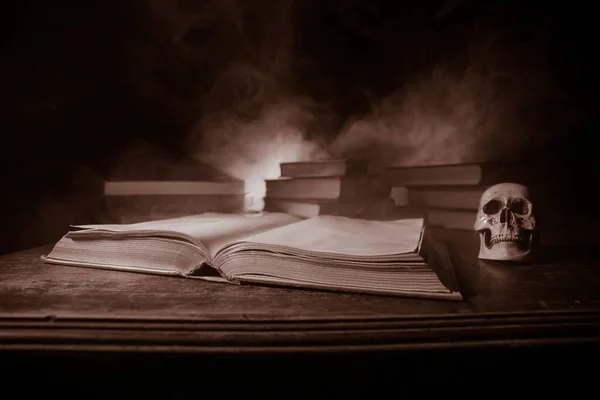 A stack of old books. Vintage book on wooden table. Magic lightning around a glowing book in the room of darkness. Selective focus